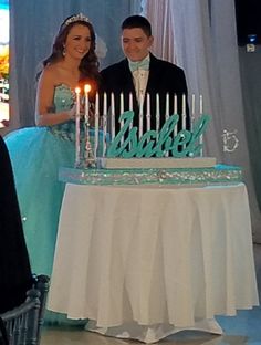 a man and woman standing in front of a cake with lit candles on top of it