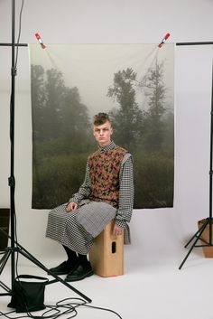 a man sitting on top of a wooden box in front of a photo studio backdrop