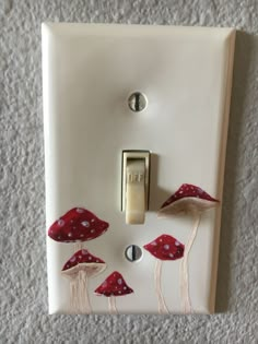 a light switch with red mushrooms painted on it