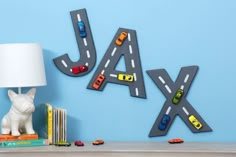 a lamp sitting on top of a book shelf next to a wall mounted letter with cars