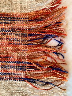 an orange, white and blue woven piece of cloth with fringes on top of it