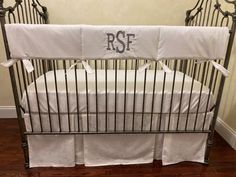 a baby crib with white sheets and monogrammed bedding on the bottom