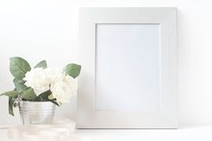 there is a vase with white flowers next to a framed photo