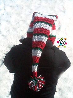 a person wearing a red, white and green knitted hat with pompom