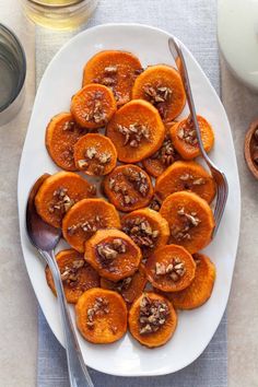 a white plate topped with cut in half sweet potatoes and nuts next to a glass of milk