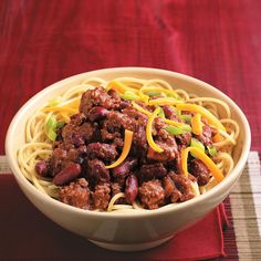 a bowl of chili beef and noodles next to a box of cheesy pasta