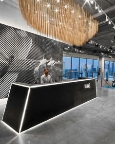 a man standing in front of a black and white reception desk with bamboo sticks hanging from the ceiling