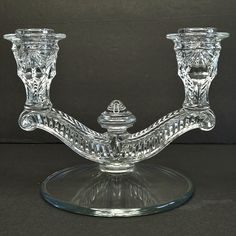 two clear glass candlesticks sitting on top of a table