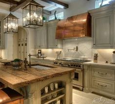 a kitchen with an island made out of wood and lights hanging from it's ceiling