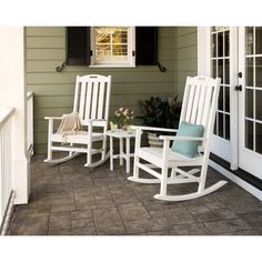 three white rocking chairs sitting on a porch