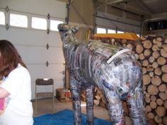 a woman standing next to a cow made out of plastic bottles