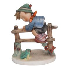 This charming Hummel figurine is made of porcelain / ceramic. This beautiful figurine with the title " Retreat to Safety " and style number #201 is a brilliantly hand sculpted and painted depiction of a young boy on a fence and a frog, the boy avoiding the frog below him. The piece is stamped as being made in West Germany with the Goebel stamp, and the back has the label M.J. Hummel, see pictures.  The measurement: height=5.5" width=4.5" depth=3.25" approx. Goebel Hummel, Label M, Hummel Figurines, A Frog, M J, The Frog, West Germany, The Boy, Porcelain Ceramics