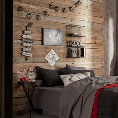 a bedroom with wooden walls and grey bedding