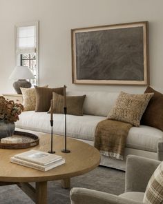 a living room filled with furniture and a painting on the wall above it's windows