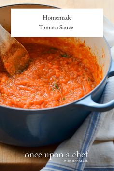 a blue pot filled with tomato sauce and a wooden spoon