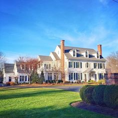 a large white house sitting on top of a lush green field