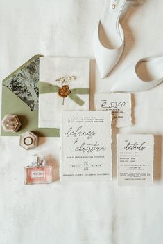 the wedding stationery is laid out with shoes, rings and other items on it