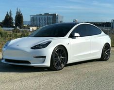 a white tesla model 3 is parked on the side of the road