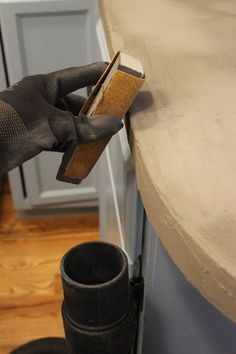 a pair of gloves is holding a piece of wood in front of a cabinet door