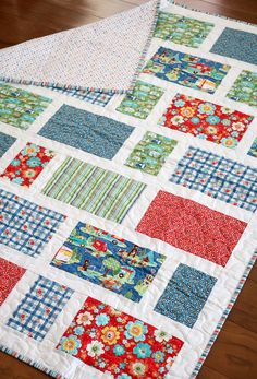 a quilted table runner on top of a wooden floor with red, blue and green squares