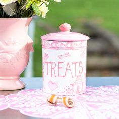 a pink cookie jar sitting on top of a table next to a vase filled with flowers