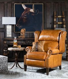 a living room with a cow painting on the wall and leather chairs in front of it