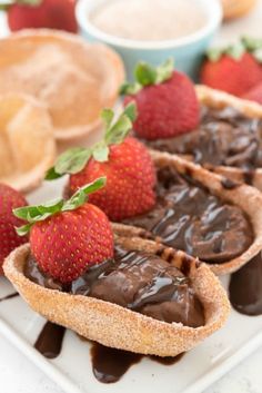 chocolate dessert with strawberries on the side sitting on a white plate next to other pastries