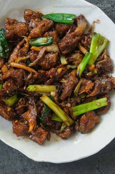 beef and vegetable stir fry with chopsticks in a white bowl