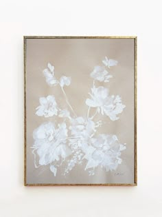 a white flower in a gold frame on a wall