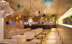 a room filled with lots of white chairs and hanging lights