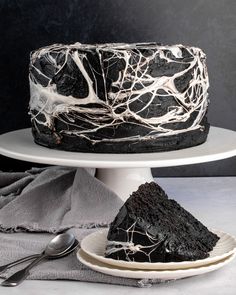 a black cake with white icing sitting on top of a plate next to a fork