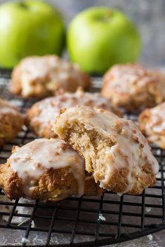 some apples are sitting on a cooling rack and one is bitten into the other with icing