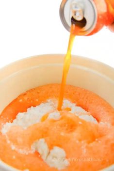 an orange drink being poured into a white cup filled with sugar and other things in it