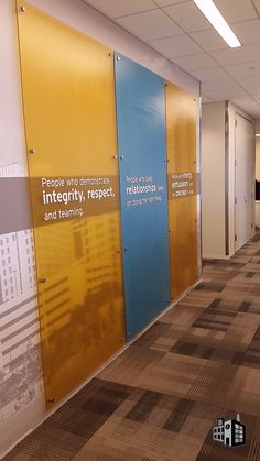 an office hallway with colorful partitions and carpeted flooring that has people who demonstrate intrepitivity, respect, and learning written on the walls