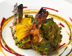 a white plate topped with broccoli covered in sauces and a yellow flower