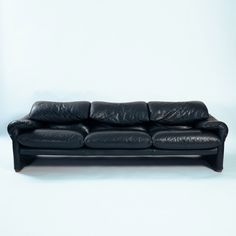 a black leather couch sitting on top of a white floor