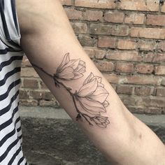 a woman's arm with a flower tattoo on the left side of her arm