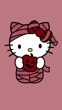 hello kitty holding a pumpkin in her hand and wearing a knitted scarf on top of it