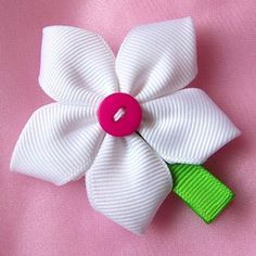 a white and green flower with a pink center on a pink cloth material background,