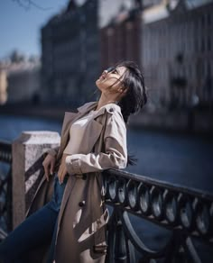 a woman leaning on a railing with her eyes closed and looking up at the sky