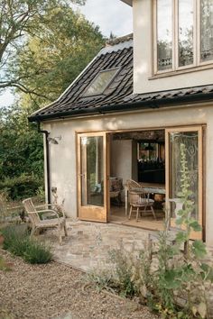 a house with an open patio and stone walkway leading to the front door, surrounded by greenery