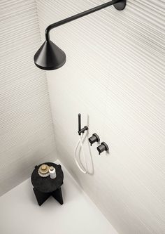 a black and white bathroom with a shower head, soap dispenser and two faucets