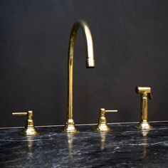 three golden faucets sitting on top of a black counter