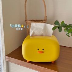 a yellow ducky shaped tissue dispenser on top of a wooden shelf