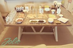 a wooden table topped with lots of food next to bottles of water and glasses on top of it