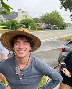 a man wearing a hat standing next to a woman on the side of a road