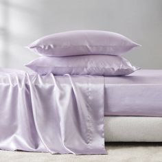 a bed with purple sheets and pillows on it