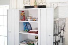 a white book shelf filled with books next to a window