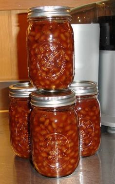 four jars filled with beans sitting on top of a counter