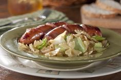 two sausages on top of cabbage in a green bowl next to some toasted bread